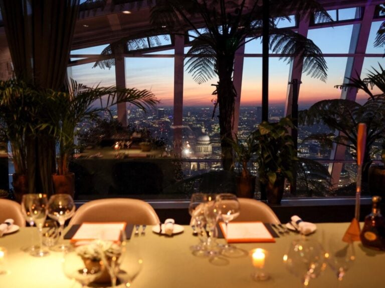A dining table at Fenchurch overlooking Sky Garden and London at sunset