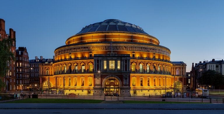 Royal Albert Hall illuminated at dusk, viewed from Kensington Gardens